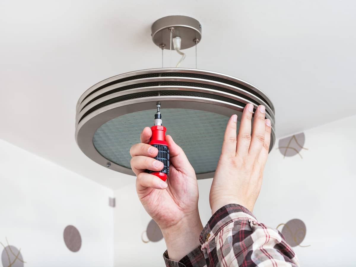 Hands mounting a round ceiling light fixture.